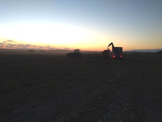 Fieldwork at dusk Agricultural machinery working at sunset on a large farm